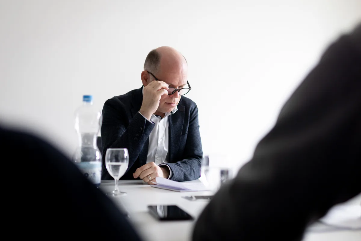 Ein Mann mit Brille sitzt vor seinen Unterlagen. 